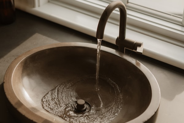 Bronze faucet with running water in residential sink